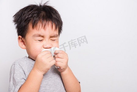 特写亚洲人脸，小男孩用组织清洁鼻子