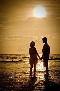 情侣在海滩上与日落的浪漫场景
