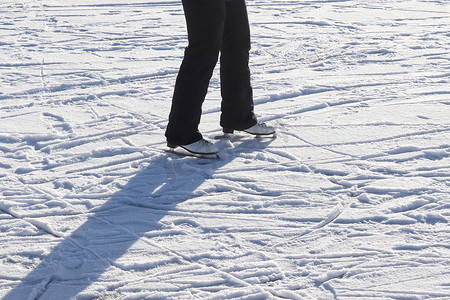 紧靠穿着滑冰靴站在冰上的女人脚。