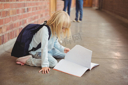 可爱的学生跪在走廊的记事本上