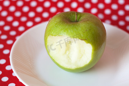 红色背景中白盘子上的青苹果