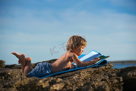 在沙滩上看书的小男孩