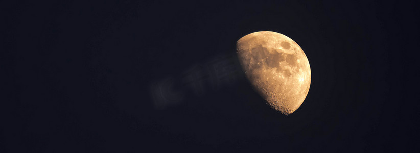 夜间在晴朗的天空中看到的黄色半月的极端变焦远摄照片