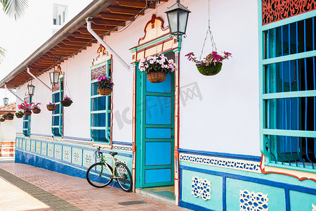 白瓜摄影照片_在 Guatape 一座美丽的蓝白相间的房子旁边骑自行车