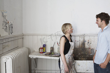 艺术工作室脏水槽旁聊天的两名大学生侧视图
