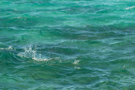 美丽清澈的绿松石海水表面的照片特写，海景背景上波纹低波，水平图片