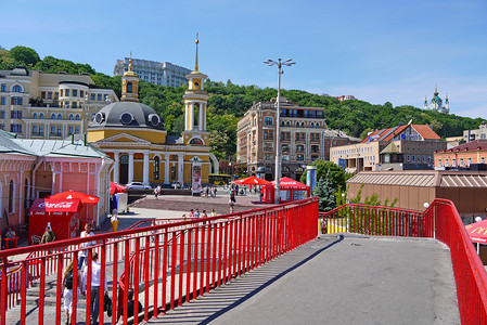 地铁入口和美丽的黄色教堂背景上带有红色围栏的人行天桥。