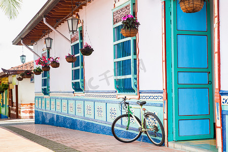 在 Guatape 一座美丽的蓝白相间的房子旁边骑自行车