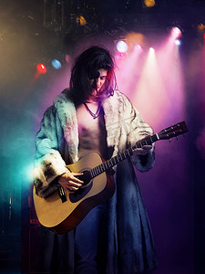 穿着皮大衣的年轻摇滚音乐家在音乐会上弹吉他