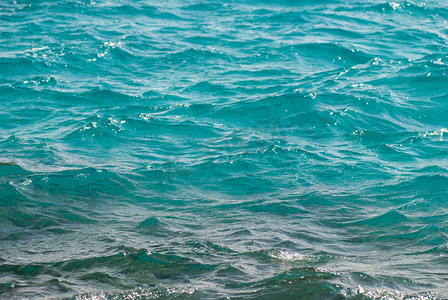 美丽清澈的绿松石海水表面的照片特写，海景背景上波纹低波，水平图片