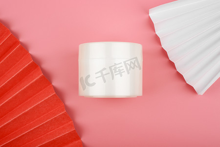 平铺着白色光滑的奶油罐，粉红色背景上装饰着白色和红色的波浪
