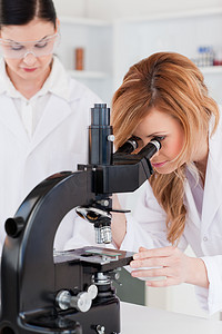 年轻科学家和她的助手一起看显微镜