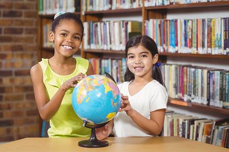 微笑的学生在图书馆学习地球仪