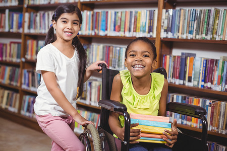 坐在轮椅上微笑的学生在图书馆拿书