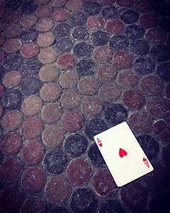 红色桃心摄影照片_脏地板上的红心王牌