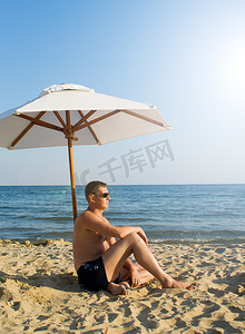 海滩上太阳伞下的男人