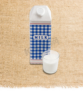 奶盒摄影照片_牛奶盒和玻璃杯，麻布上有牛奶