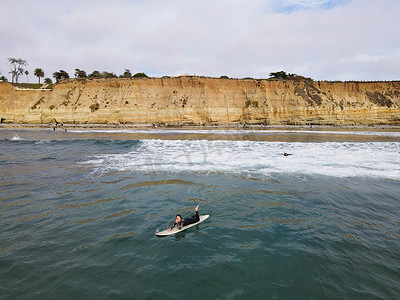 冲浪者穿着潜水衣划水，享受大浪。