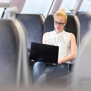 坐火车旅行的女人在笔记本电脑上工作。