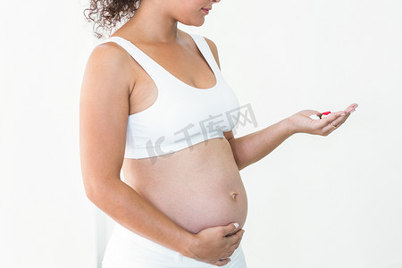孕妇生病摄影照片_拿着药丸的孕妇