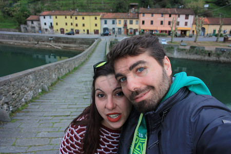 a年轻人摄影照片_年轻人通过在 Ponte della Maddalena 的 Borgo a Mozzano 的 Lucca 的 Serchio 河上游览托斯卡纳的村庄来旅行