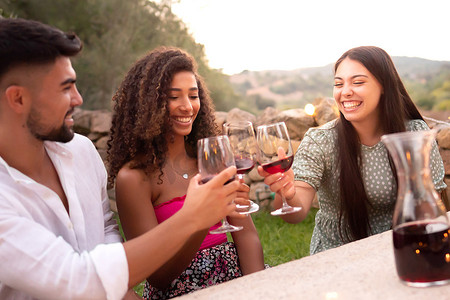三个朋友在日落时在户外碰杯 — 混血儿团体在乡村用红酒杯敬酒，以便在托斯卡纳的葡萄园收获结束 — 复古外观照片