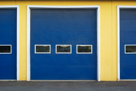 黄墙摄影照片_黄墙商业楼上的蓝色车库门