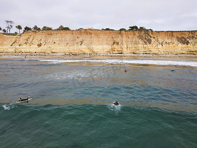 冲浪者穿着潜水衣划水，享受大浪。