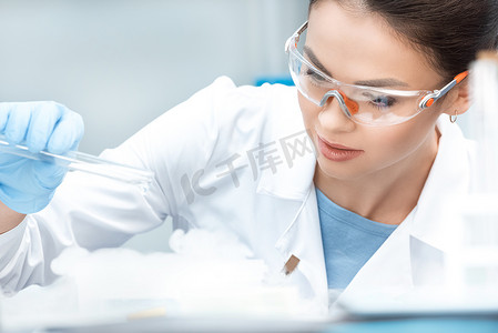 戴防护镜的年轻女化学家在实验室做实验