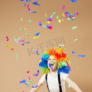 戴着小丑假发的小男孩跳跃着庆祝出生