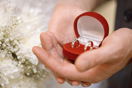 新郎和新娘的手拿着有圆环的小箱