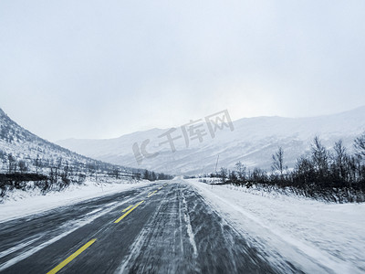 驾车穿过暴风雪暴风雪，路上有黑冰，挪威。
