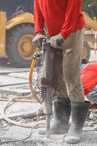 工人在地面上使用建筑钻孔水泥