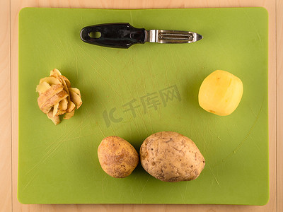 器皿摄影照片_绿色塑料板上的土豆和皮