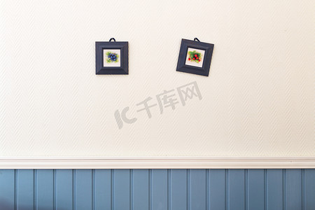 两张蓝莓和草莓的方形小画框挂在白色的蓝色墙上。