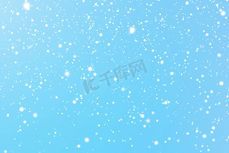 蓝色冬日雪花摄影照片_寒假和冬季背景，白雪落在蓝色背景上，雪花散景和降雪颗粒作为圣诞节和下雪假期设计的抽象下雪场景