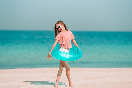 度假圈摄影照片_可爱的小女孩在度假期间在热带海滩玩得开心