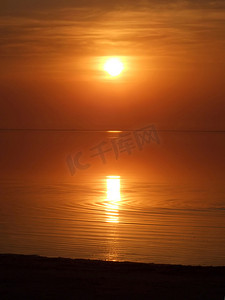 在一个安静的平静的海湾之上的橙色日落