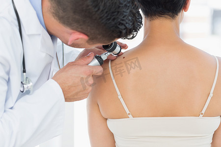 背人摄影照片_皮肤科医生检查女人背上的痣