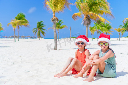 圣诞海滩假期期间，可爱的小孩戴着圣诞老人的帽子。