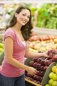 农产品商店摄影照片_在农产品柜台挑选苹果的女人