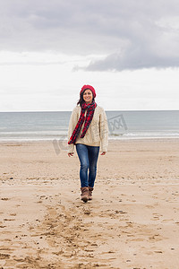 在海滩上穿着时尚保暖衣服的女人的全长