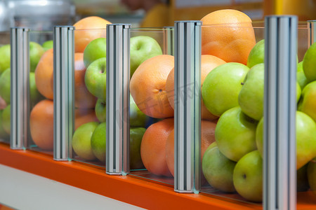 一个大玻璃容器展示新鲜水果苹果和橙子，焦点放在橙子上