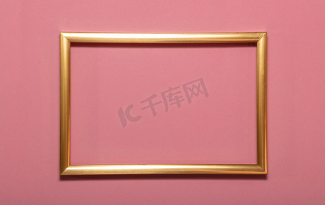 粉红色背景上的金色空框图片。