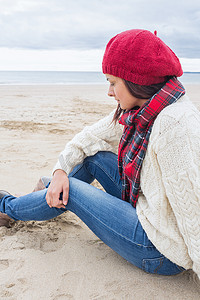 穿着时髦保暖衣服的女人坐在沙滩上