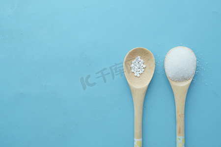 人造甜味剂摄影照片_人造甜味剂容器与木勺上的白糖比较
