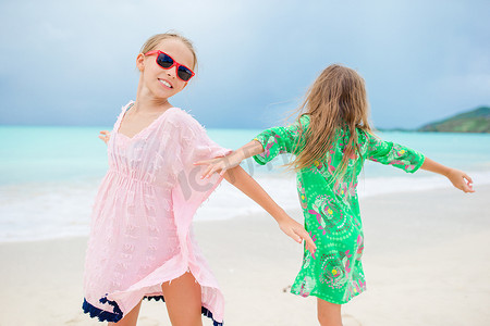 快乐的女孩们在热带海滩上玩得开心，享受假期，那里有白色的沙滩和碧绿的海水