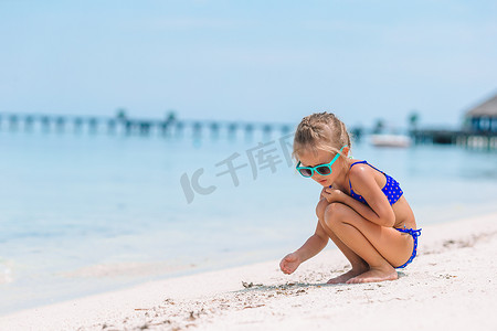 可爱的小女孩在白色的沙滩上画画