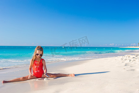 小女孩坐在白色沙滩的裂缝上