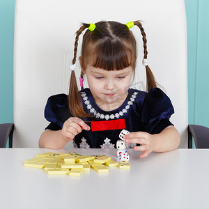 玩玩具的小女孩摄影照片_坐在桌边玩玩具的小女孩